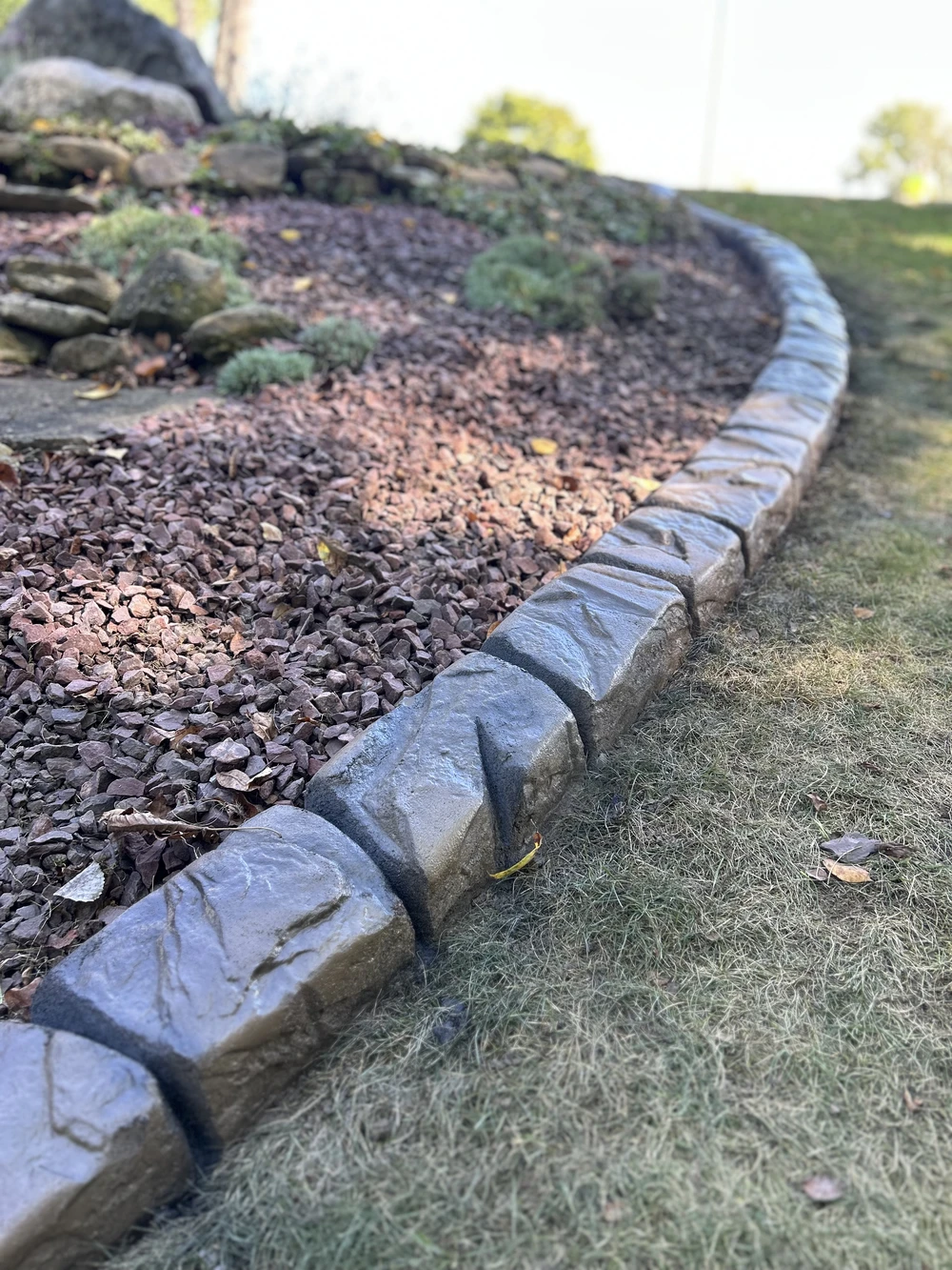 Curbscapes Outdoors landscaping fort wayne in 1 - Curbscapes Outdoors Curved concrete curbing frames a mulched foundation bed with shrubs beside a covered front porch.