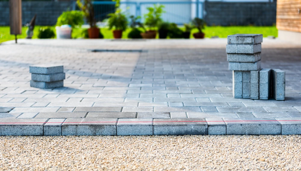 Curbscapes Outdoors pavers fort wayne in 5 - Curbscapes Outdoors Gray pavers patio installation with stacked blocks and a straight layout line beside a finished lawn.
