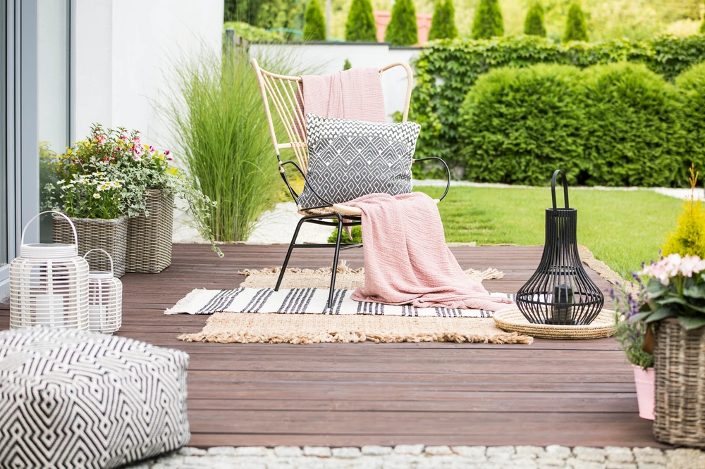 curbscapefw deck construction fort wayne in 1 - Curbscapes Outdoors Cozy deck construction with chair, lanterns, rugs, and planters styled for a modern backyard retreat.