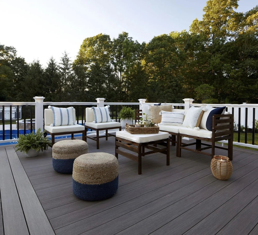 Curbscapes Outdoors hardscaping huntertown in 1 - Curbscapes Outdoors Dark brown deck with white rail posts and cream seating overlooks a blue pool and green trees.