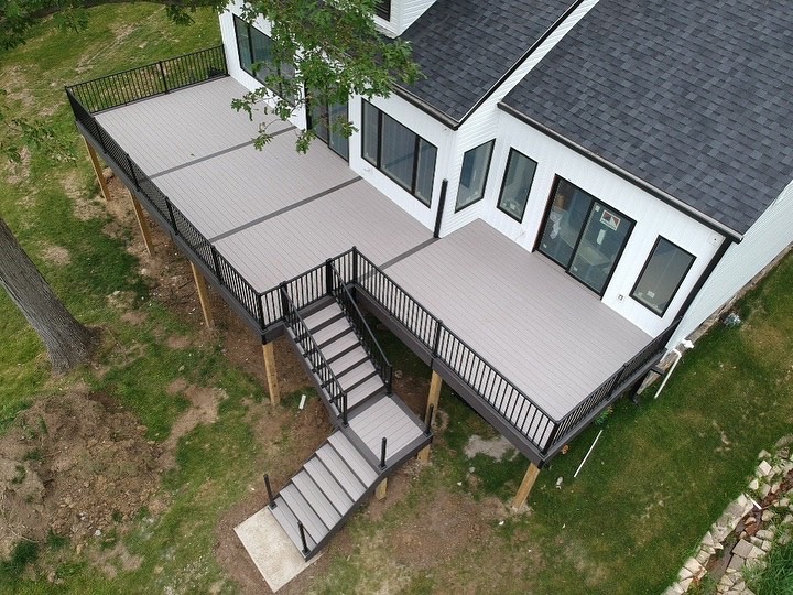 curbscapes blog week1 4 - Curbscapes Outdoors Aerial view of a pale gray deck wrapping around a white house. Black railings and a central staircase define the broad angular layout.